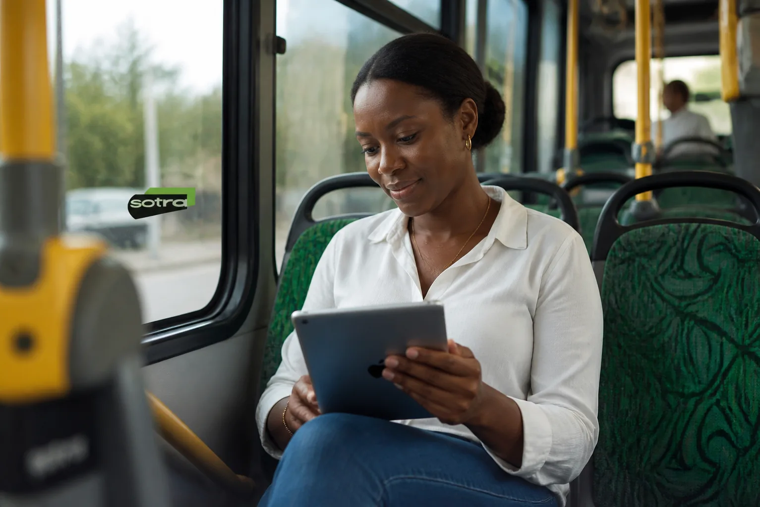 Voyageuse SOTRA consultant sa tablette dans un bus